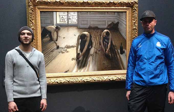 Deux apprentis en pose du parquet devant un tableau de Gustave Caillebotte dédié aux raboteurs